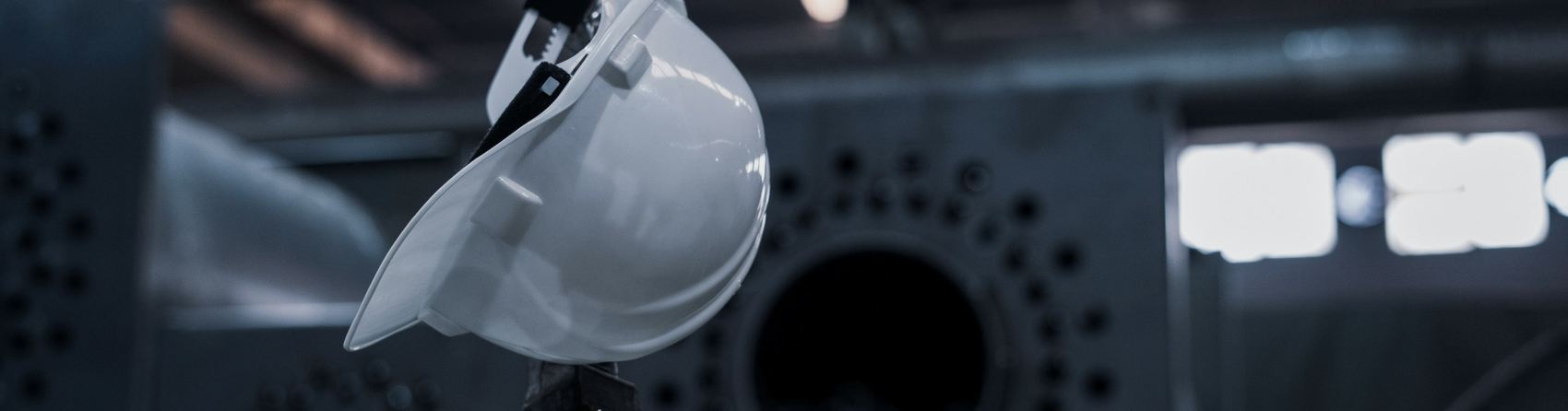 Casque de protection suspendu devant une machine industrielle